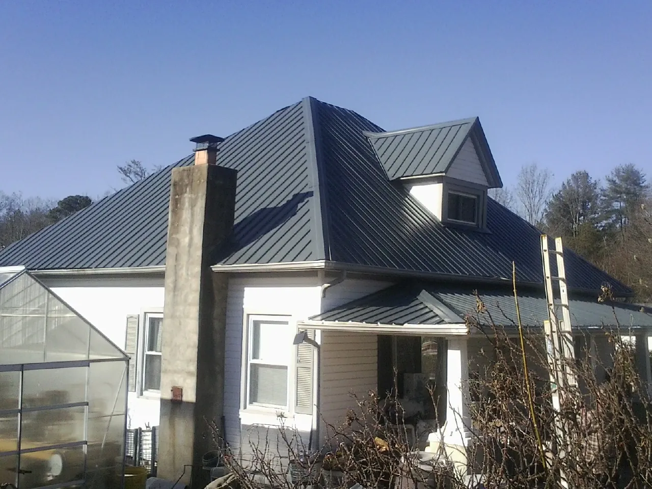 Dark blue standing seam metal roof on a white farmhouse with dormer — Slate & Tile Roof Repair by Roofing Brothers in Gaylordsville