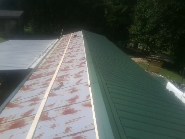 Old rusted panels beside newly installed green metal roofing — Wind Damage Roof Repair by Roofing Brothers in Gaylordsville