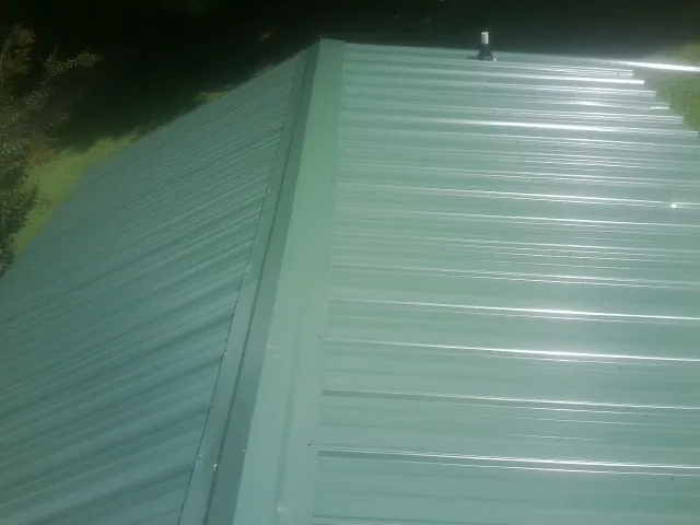 New green metal panels meeting at the ridge of a roof — Flat Roof Repair work by our crew in Gaylordsville