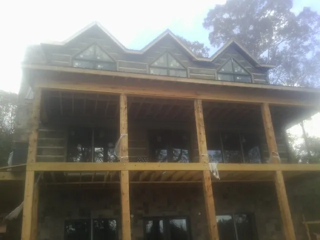 Dormers and porch framing on a large log home under construction — Roof Coating work by our crew in Gaylordsville