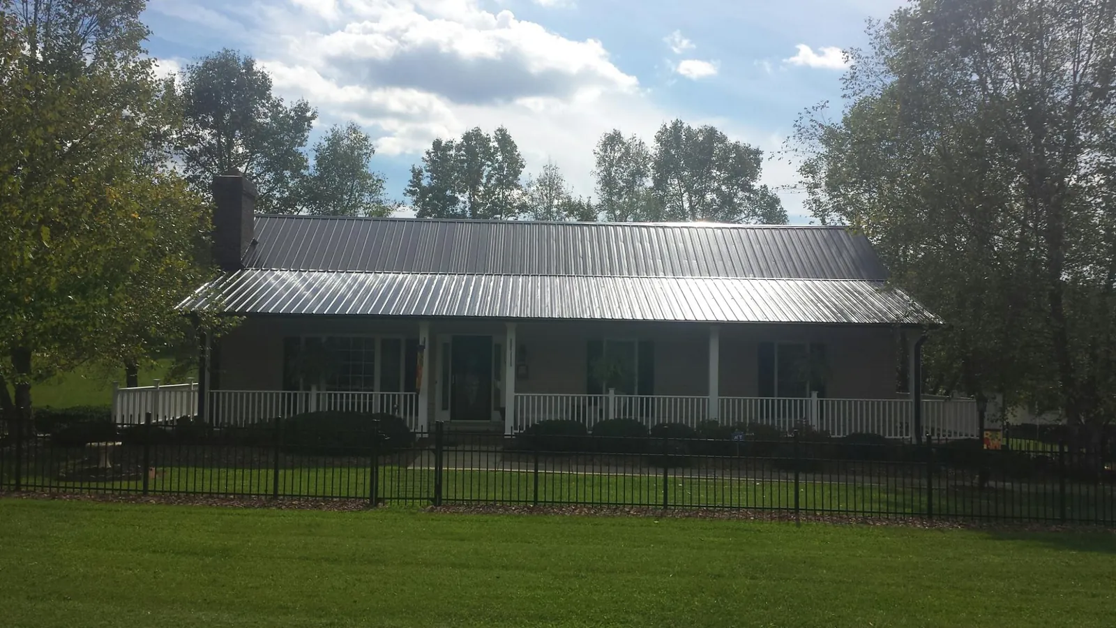 Gray metal roof on a brick ranch with a full width front porch — Gutter Guard Installation work by our crew in Gaylordsville