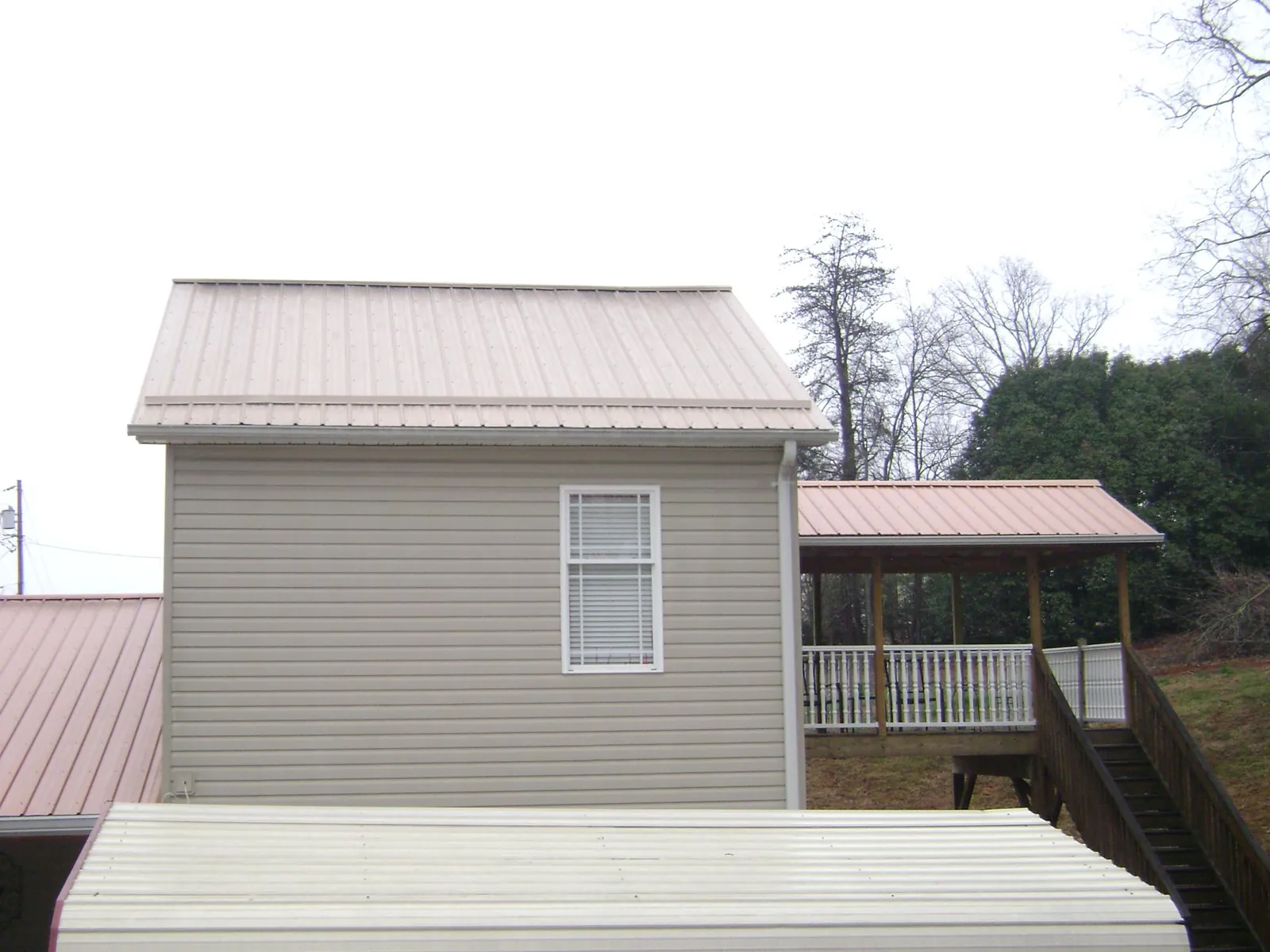 Tan metal roofs on a two story addition and attached porch, from a Roof Replacement job in Gaylordsville