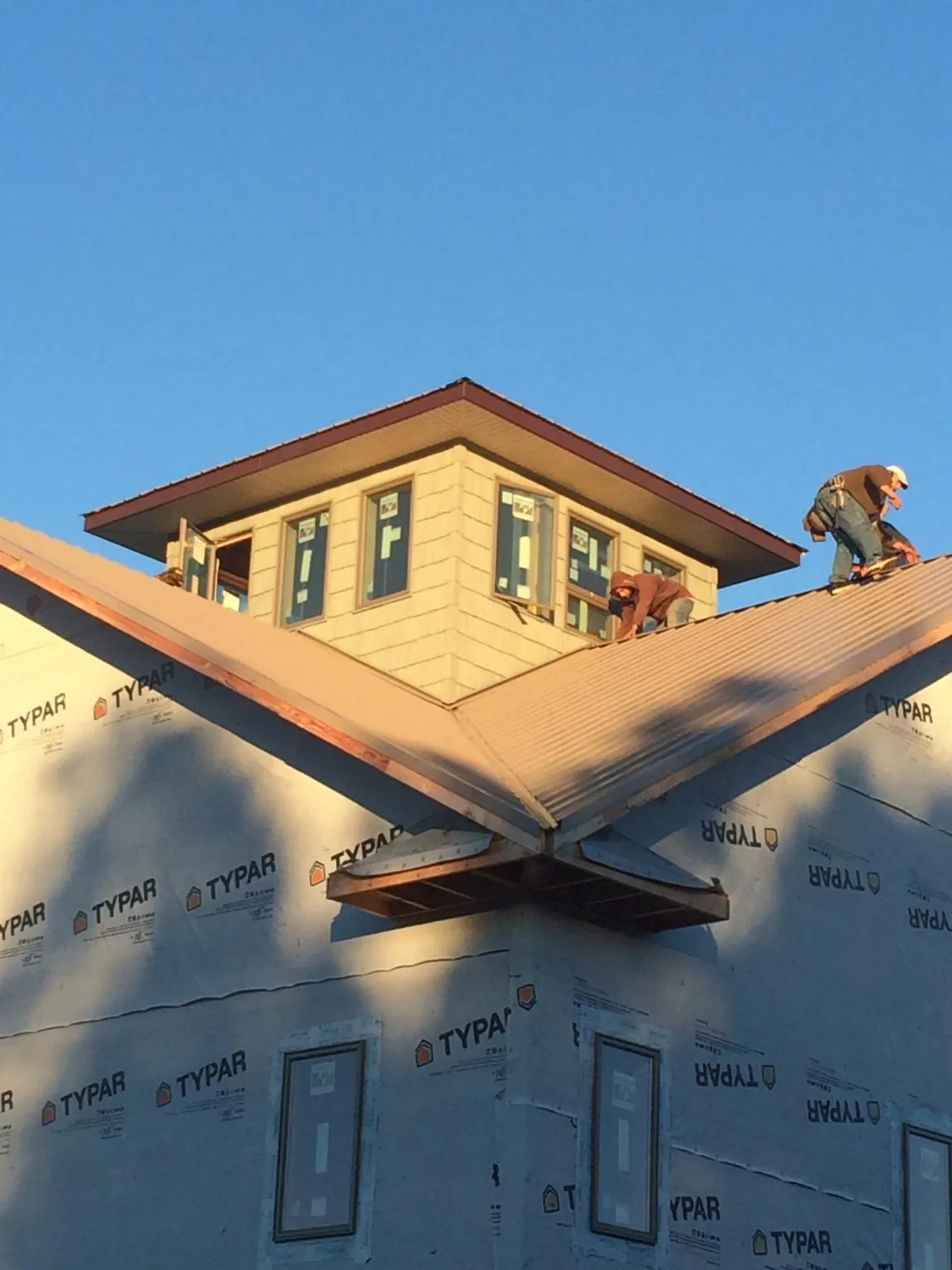 Roofers working around a rooftop cupola on a new metal roof at sunset — Roof Waterproofing in Gaylordsville by Roofing Brothers
